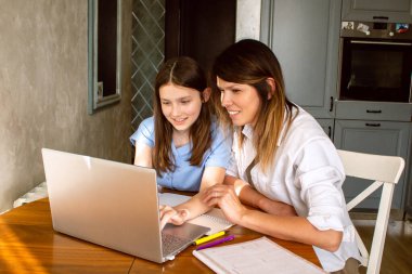 Kızı, internette dizüstü bilgisayarda heyecanlı bir şey gösteriyor. Mutfakta masada oturuyor. Ebeveynliğin ve anneliğin kutlu olsun. Mutlu aile kavramı