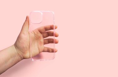 Pembe arka planda el ele tutulan şeffaf telefon kılıfı, temiz tasarım ve işlevselliği gösteriyor, stil ve zarafeti korurken aygıtları korumak için ideal