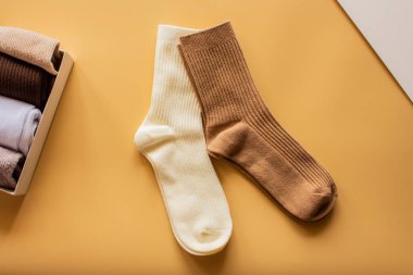 Çağdaş tekstil tasarımı ve konforlu moda tercihlerinin vurgulanması için parlak sarı yüzeye yerleştirilmiş, krem ve kahverengi renkli şık tırtıklı çoraplar.