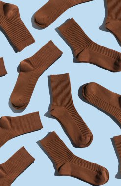 Açık mavi arka planda şakacı desenli kahverengi çoraplar, moda ve tekstil uygulamaları için ideal desen ve tasarım sergileniyor. Dikey