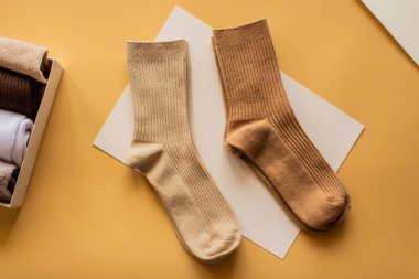 Sarı arka planda bej ve kahverengi renkli iki çift tırtıklı çorap, moda ve yaşam tarzı kavramları için ideal tekstil dokusu ve tasarımı sergiliyor..