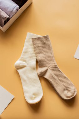 Sıcak sarı arka planda, kremalı ve bej renkli bir çift uzun çorap. Rahatlık, sıcaklık ve minimalist moda temaları için mükemmel. Dikey