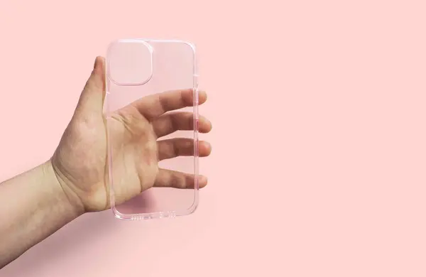 Pembe arka planda el ele tutulan şeffaf telefon kılıfı, temiz tasarım ve işlevselliği gösteriyor, stil ve zarafeti korurken aygıtları korumak için ideal