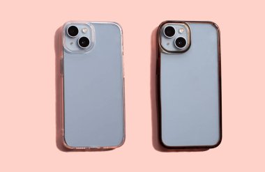 İki akıllı telefon çantası, biri şeffaf ve biri koyu, yumuşak pembe bir arka planda sergileniyor, modern tasarım ve mobil cihazlar için koruyucu özellikler sergileniyor