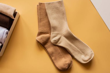 Sarı arka planda sergilenen, bej ve açık kahverengi renkli, rahat çoraplar, moda ve konfor için dokuları ve sıcaklığı gösteren..