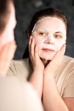 Kadının dikkatlice yerleştirdiği yüz maskesi. Düzgün cilt bakımını göstermek için kullanışlı. Kişisel bakım kavramı