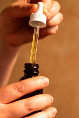 Kadın eli dikkatlice cam pipetle aromatik vücut yağını döküyor. Spa, aromaterapi, kişisel bakım konsepti. Uluslararası Kişisel Bakım Günü