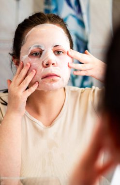 Kadın banyoda nemlendirici yüz maskesi takıyor. Güzellik rutini. Uluslararası Kişisel Bakım Günü