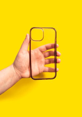 Canlı sarı bir arka plana karşı şeffaf bir akıllı telefon çantası, modern tasarım ve mobil cihaz koruması ve stil geliştirme işlevselliği sergileniyor