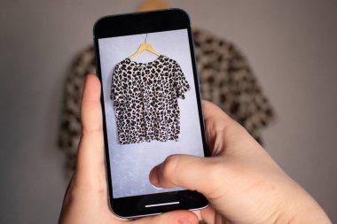 Satılık eski kıyafetlerinin fotoğrafını çeken bir kadın. İkinci el konsepti. Dolap organizasyonu.