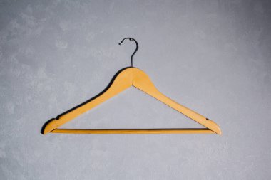 Ahşap elbise askısı gri duvara dayanıyor. Minimalizm kavramı.