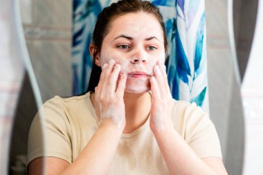 Lavaboda köpük temizleyicisiyle cilt bakımı yapan genç bir delikanlı. Gen Z güzellik eğilimleri veya gençlik hijyen eğitimi için ideal