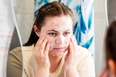 Kadının nazikçe yüzünü temizleyen ve temizleyici köpükle masaj yapan yüzünün yan görüntüsü. Güzellik markaları, cilt bakımı adımları veya hijyenle ilgili içerikler için kullanışlı. Uluslararası kişisel bakım günü