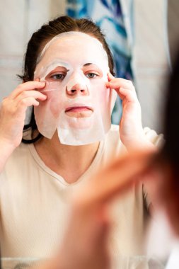 Kadının dikkatlice yerleştirdiği yüz maskesi. Düzgün cilt bakımını göstermek için kullanışlı. Kişisel bakım kavramı