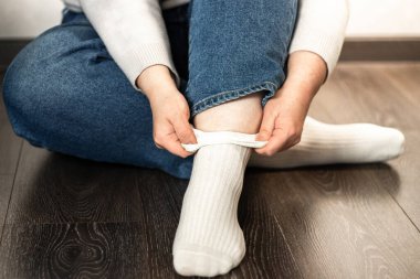 Yerde otururken temiz beyaz çoraplar giyen genç bir kadının yakın çekimi. Yaşam tarzı, konfor ve günlük rutin temalar için mükemmel.