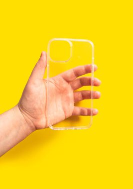 Parlak sarı bir arkaplana karşı şeffaf bir akıllı telefon çantası, modern tasarım ve mobil cihaz koruması ve stil geliştirme işlevselliğini gösteriyor