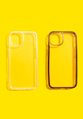 Şeffaf telefon kılıflarının karşılaştırılması, bir temiz ve bir kirli, parlak sarı arka planda sergilenen, mobil aksesuarların günlük kullanımının etkisini gösteren.