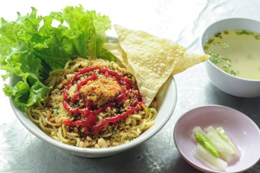 Mie ayam (tavuk, köfte, mantı ve sebzeli erişte) Endonezya 'da popüler bir sokak yemeğidir. Tahta masada kasede servis edilmiş. Seçili odak.