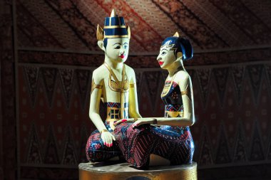Sarışın loro ya da geleneksel Java düğün bebekleri sunakta Batik kumaşın önünde yan yana otururlar.