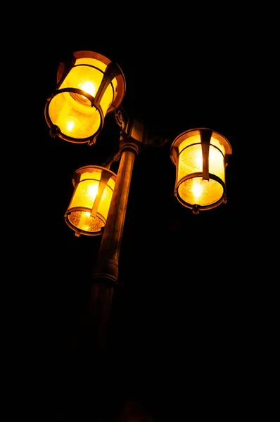 A garden lamp lights up at night, beautifully dim in the darkness of the night