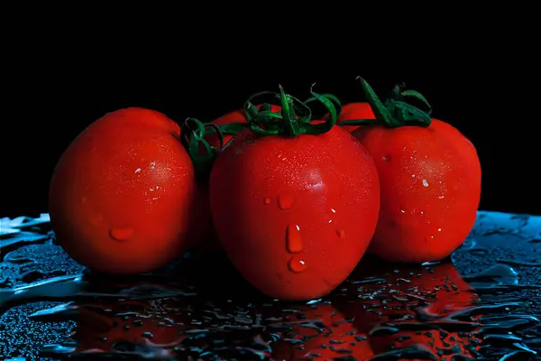 Several tomatoes are neatly arranged on a watery glass table. Fresh and reflective