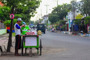 Pasuruan, Endonezya - 15 Şubat 2012: Yol kenarındaki genç hindistan cevizi buzu satıcısı mallarını hazırlıyor