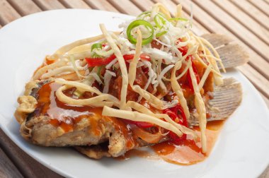 Kızarmış unla süslenmiş baharatlı ve ekşi soslu Gurame balığı.