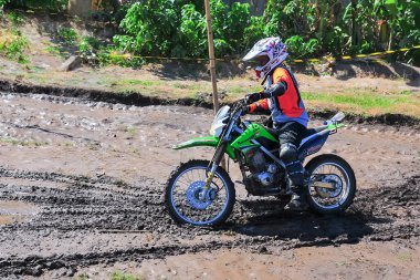 Probolinggo, Endonezya - 8 Temmuz 2012: Çamurlu zeminde bir motokros yarışçısı sürüyor