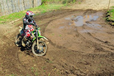 Probolinggo, Endonezya - 8 Temmuz 2012: Bir motokros yarışçısı çamurlu bir köşede araba sürüyor