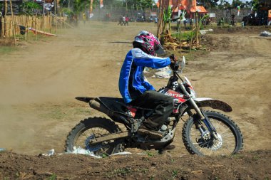 Probolinggo, Endonezya - 8 Temmuz 2012: bir motokros yarışçısı tozlu bir köşe pistini denemek için antrenman yapıyor