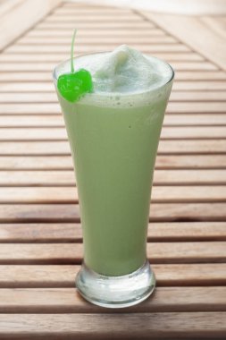 Buzlu Vanilyalı Yeşil Çay ahşap bir masaya konur.