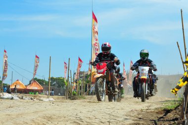 Probolinggo, Endonezya - 8 Temmuz 2012: Bir motosiklet çapraz yarışçısı tozlu bir pistte pratik yapıyor