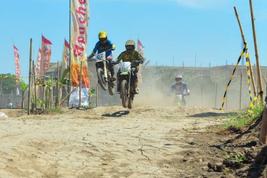 Probolinggo, Endonezya - 8 Temmuz 2012: Bir motosiklet çapraz yarışçısı tozlu bir pistte pratik yapıyor