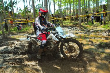 Probolinggo, Endonezya - 8 Temmuz 2012: Çamurlu bir pistte bir motosiklet yarışçısı pratik yapıyor