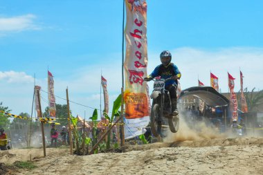 Probolinggo, Endonezya - 8 Temmuz 2012: Bir motosiklet çapraz yarışçısı tozlu bir pistte pratik yapıyor