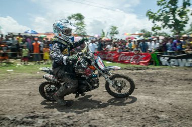 Pasuruan, Endonezya - 3 Şubat 2013: Çamurlu zeminde bir motokros yarışçısı sürüyor