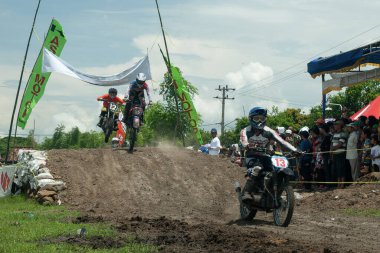 Pasuruan, Endonezya - 3 Şubat 2013: Çamurlu zeminde bir motokros yarışçısı sürüyor