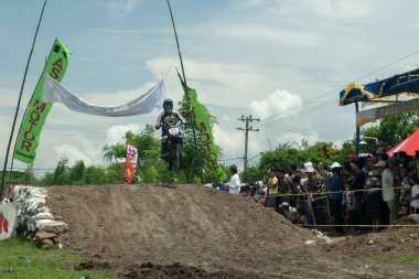 Pasuruan, Endonezya - 3 Şubat 2013: Çamurlu zeminde bir motokros yarışçısı sürüyor