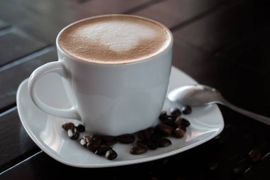 Çiçek süslemesi şeklinde kremalı bir fincan sıcak kapuçino.