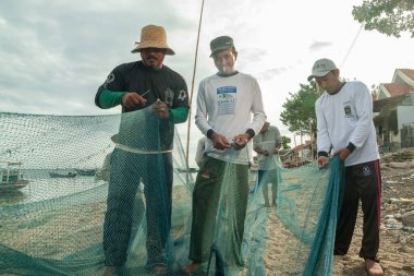 Probolinggo, Endonezya - 30 Kasım 2014: Gili Adaları 'ndaki köylülerin günlük faaliyetleri denizde balık tutmak için kullanılmadan önce balık ağlarını onarıyor