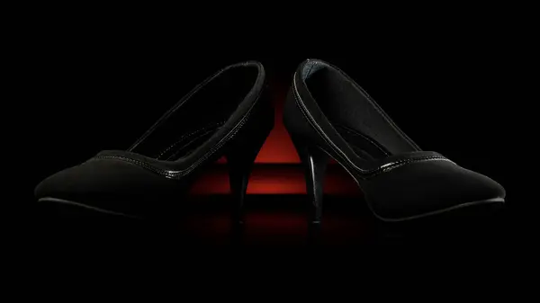 Stylish black high heels against a black backdrop