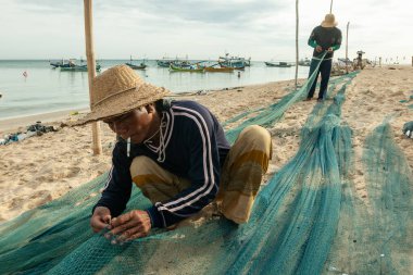 Problinggo, Endonezya - 30 Kasım 2014: Gili Adalı bir balıkçının portresi Sabah denize açılmadan önce bir balık ağını tamir ediyor