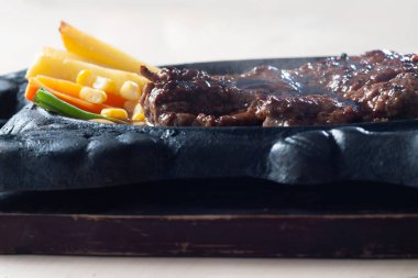 Biftek Daging Sapi Lada Hitam ya da acı tabakta Black Pepper Biftek, soğanlı ve karışık patates kızartmasıyla karıştırılmış.