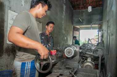 Pasuruan, Endonezya - 16 Ocak 2014: Torna atölyesinin sahibi çalışanlarını denetliyor