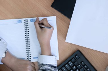 Ofis masasındaki boş bir kitaba yazı yazan elleri kapat.