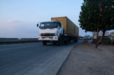Pasuruan, Endonezya - 2 Ekim 2014: Gün batımında deniz kenarında bir konteynır kamyonu sürüyor