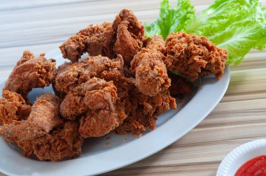 Domates soslu bir demet kızarmış tavuk. Beyaz tabakta servis edilir.