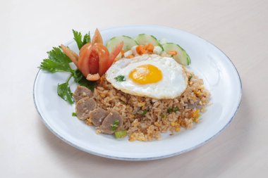 Nasi Goreng Spesial ya da Özel Kızarmış Pirinç beyaz tabakta biraz sebze ve garnitür olarak servis edilir.