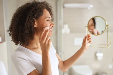 Etrafına havlu sarılmış bir kadın banyo aynasında kendine hayran. Gülümsüyor, yüzüne, boynuna ve koluna dokunuyor. Bacağına ve kalçasına doğru hareket ediyor.