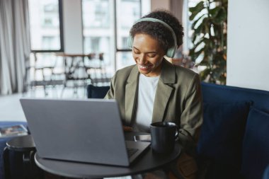 Resmi kıyafetli bir beyazlar çalışanı bir odada oturuyor, bir etkinlikteki görevlerini yerine getirmek için dizüstü bilgisayar kullanıyor.